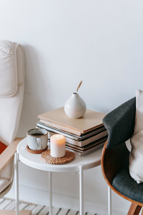 Table with tea and flaming candle between armchairs in room