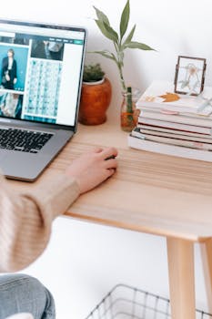 Cozy home office setup with a laptop, books, and plants on a wooden desk, perfect for remote work.