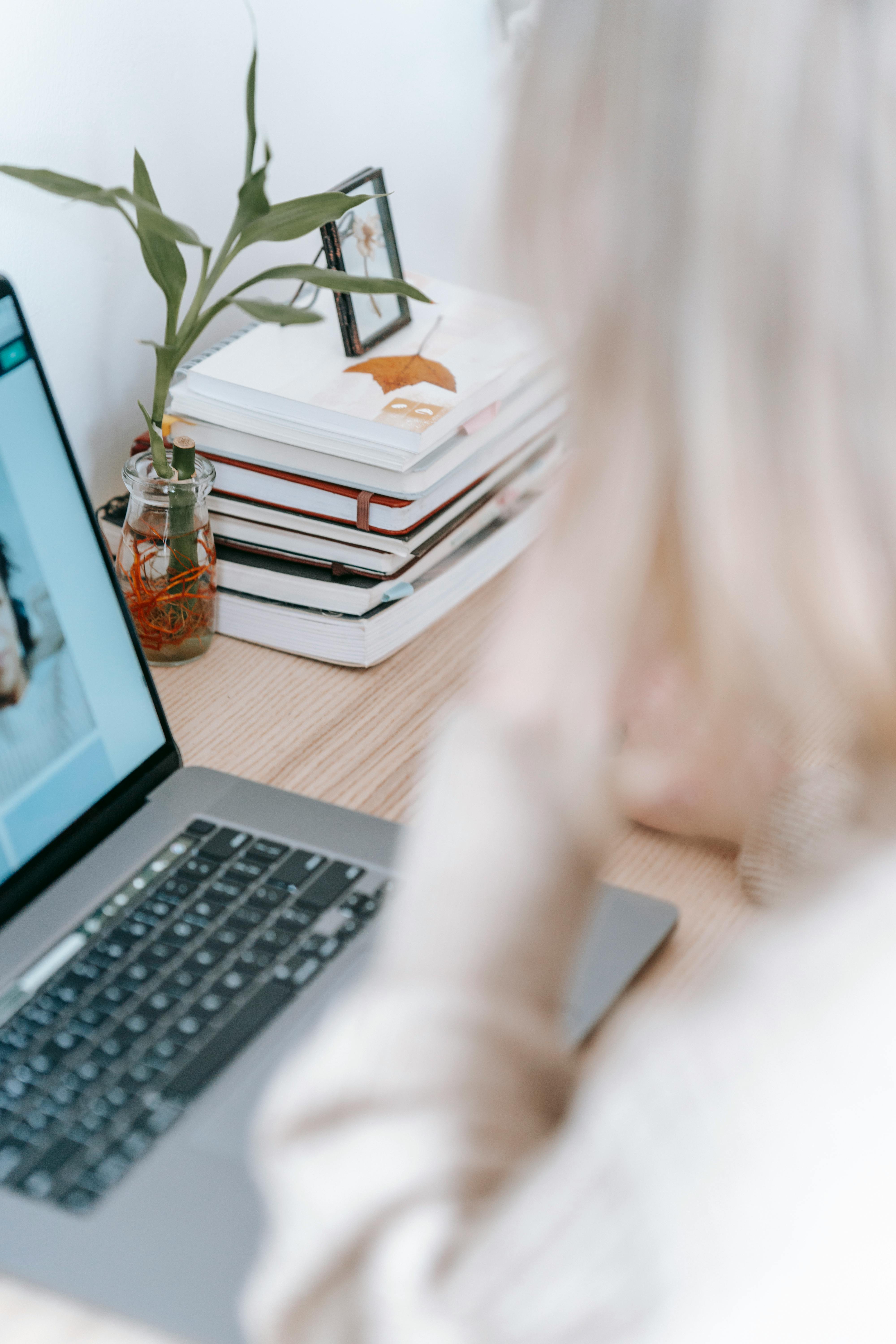 faceless distance worker against laptop and books at home