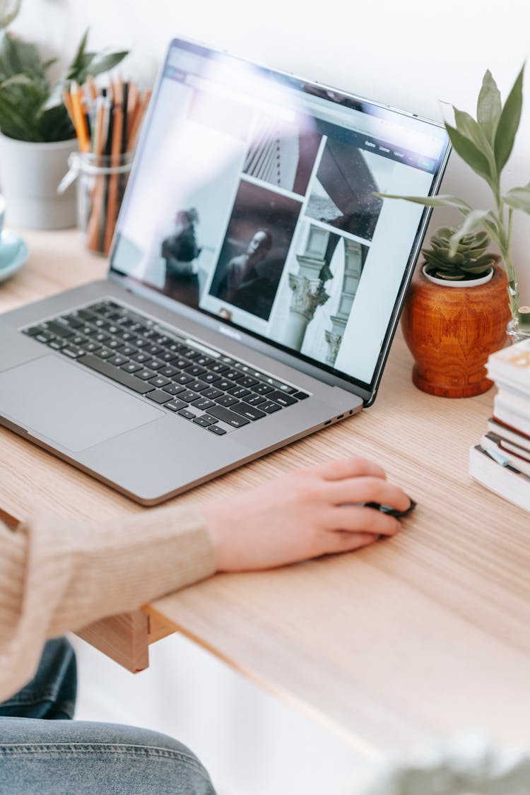 Faceless Freelancer Working On Laptop With Photos On Screen