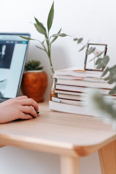 A cozy home office setup with books, plants, and a laptop for work or study.