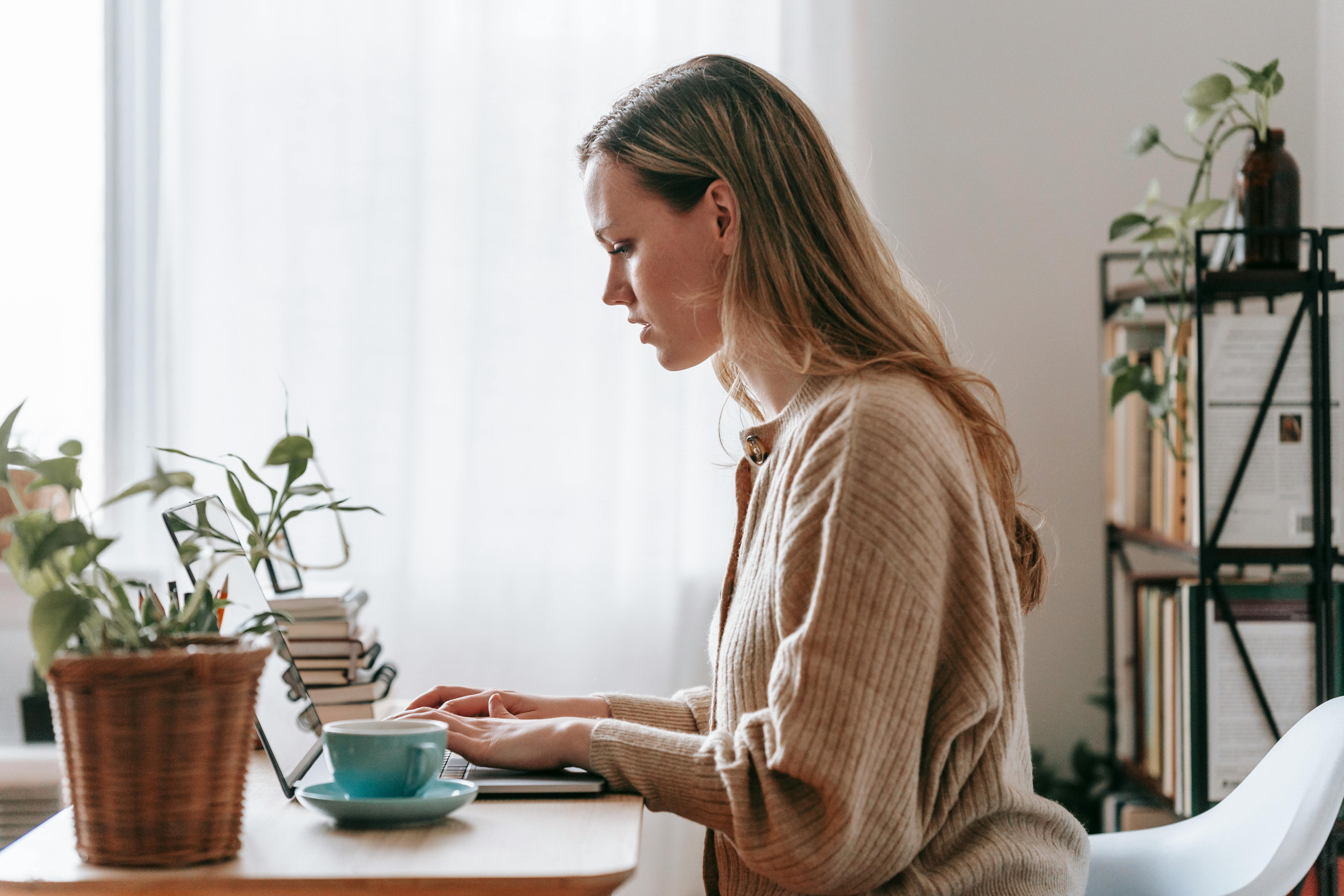 remote employee typing on laptop at desk in house