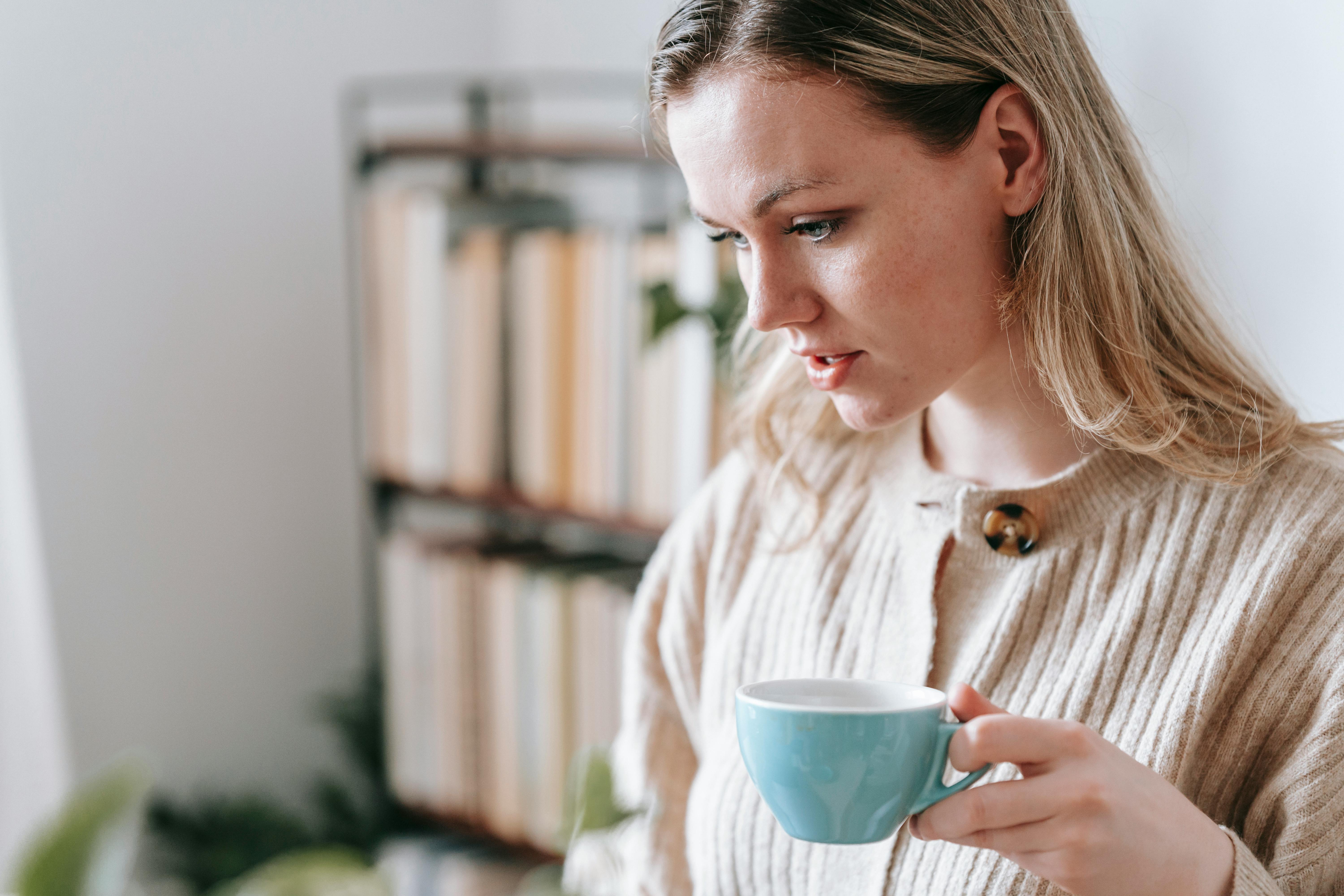 crop attentive woman with coffee at home