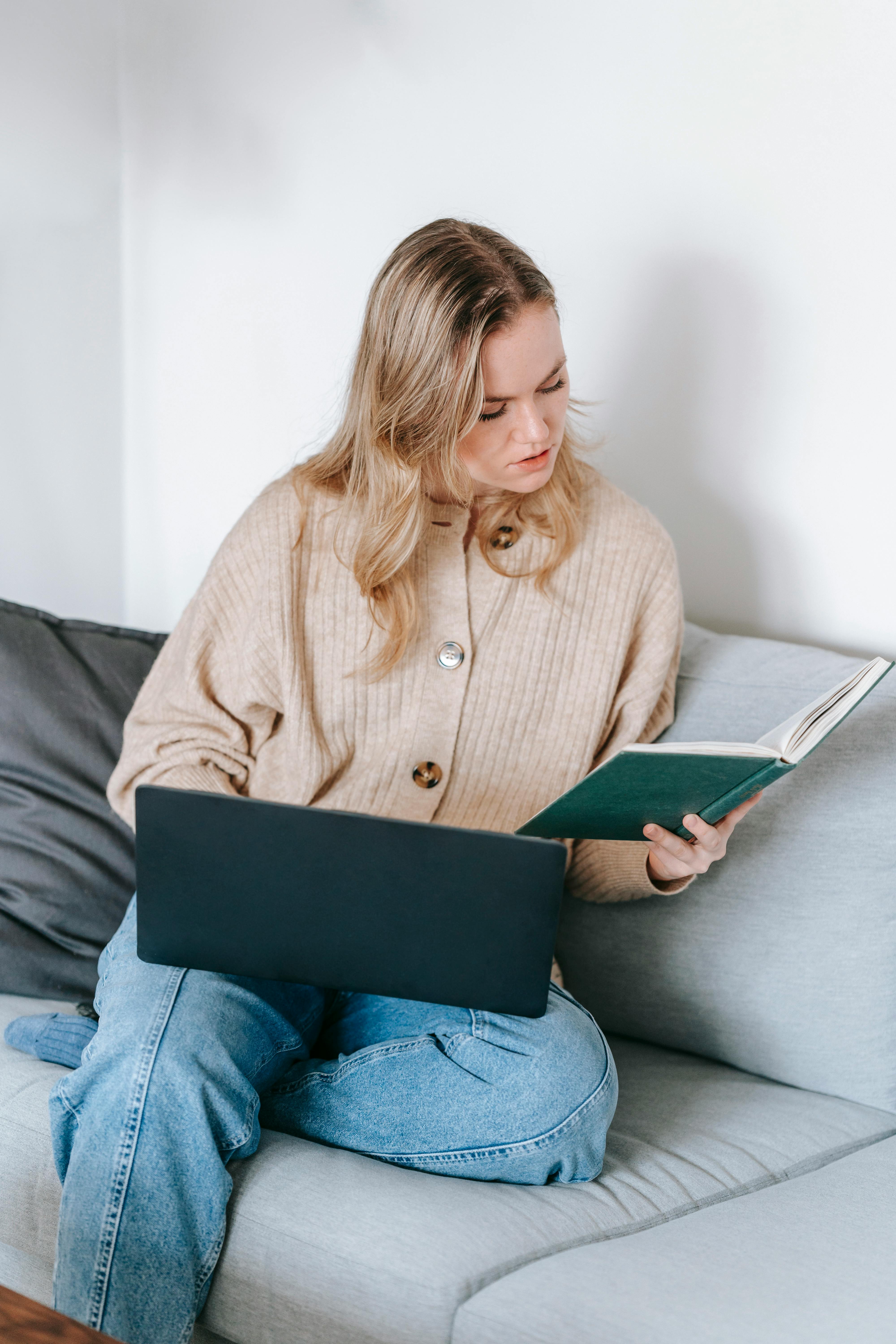 focused woman reading notebook while loading laptop