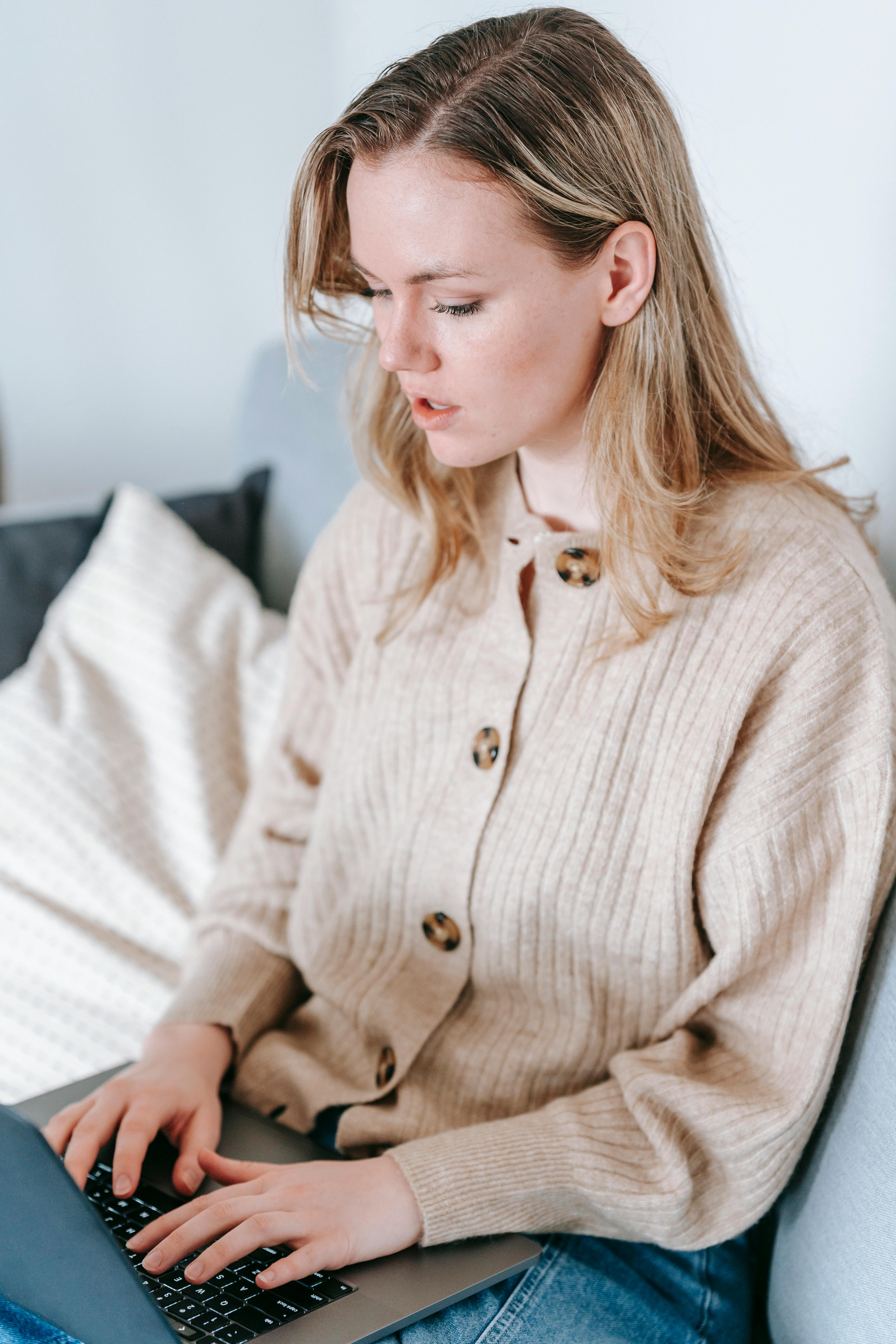 focused woman typing report on laptop at home