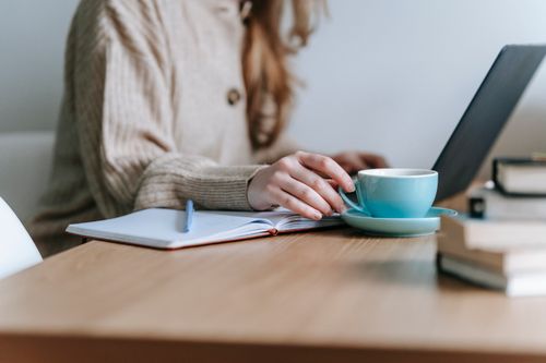 Free Crop anonymous female freelancing with netbook at table with mug of coffee on blurred background Stock Photo