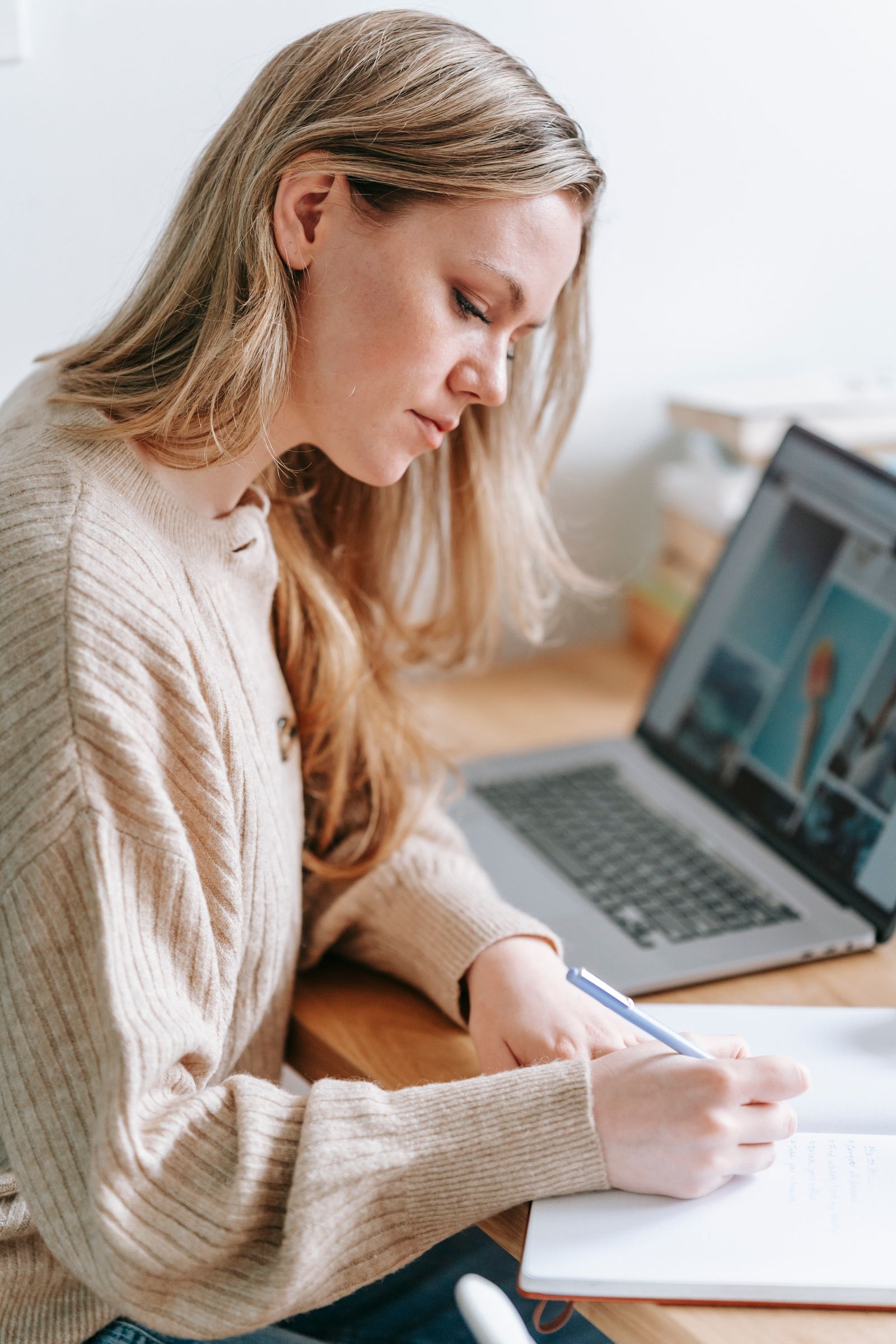 Rédactrice indépendante prenant des notes devant son ordinateur portable