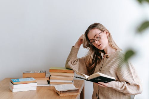 Pensive female student reading book in light room