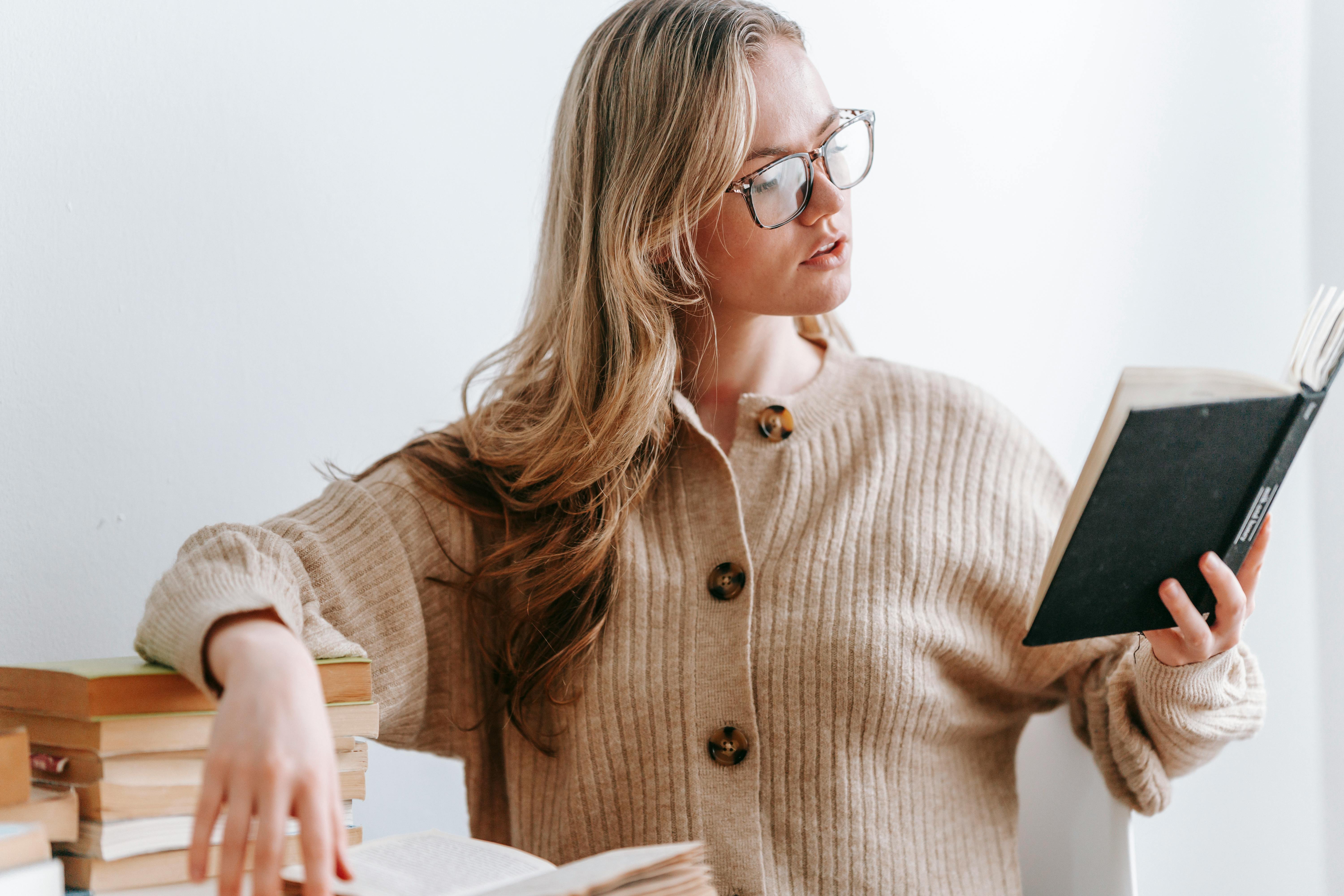 young woman in eyeglasses reading book