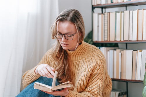 Woman in sweater and glasses with book
