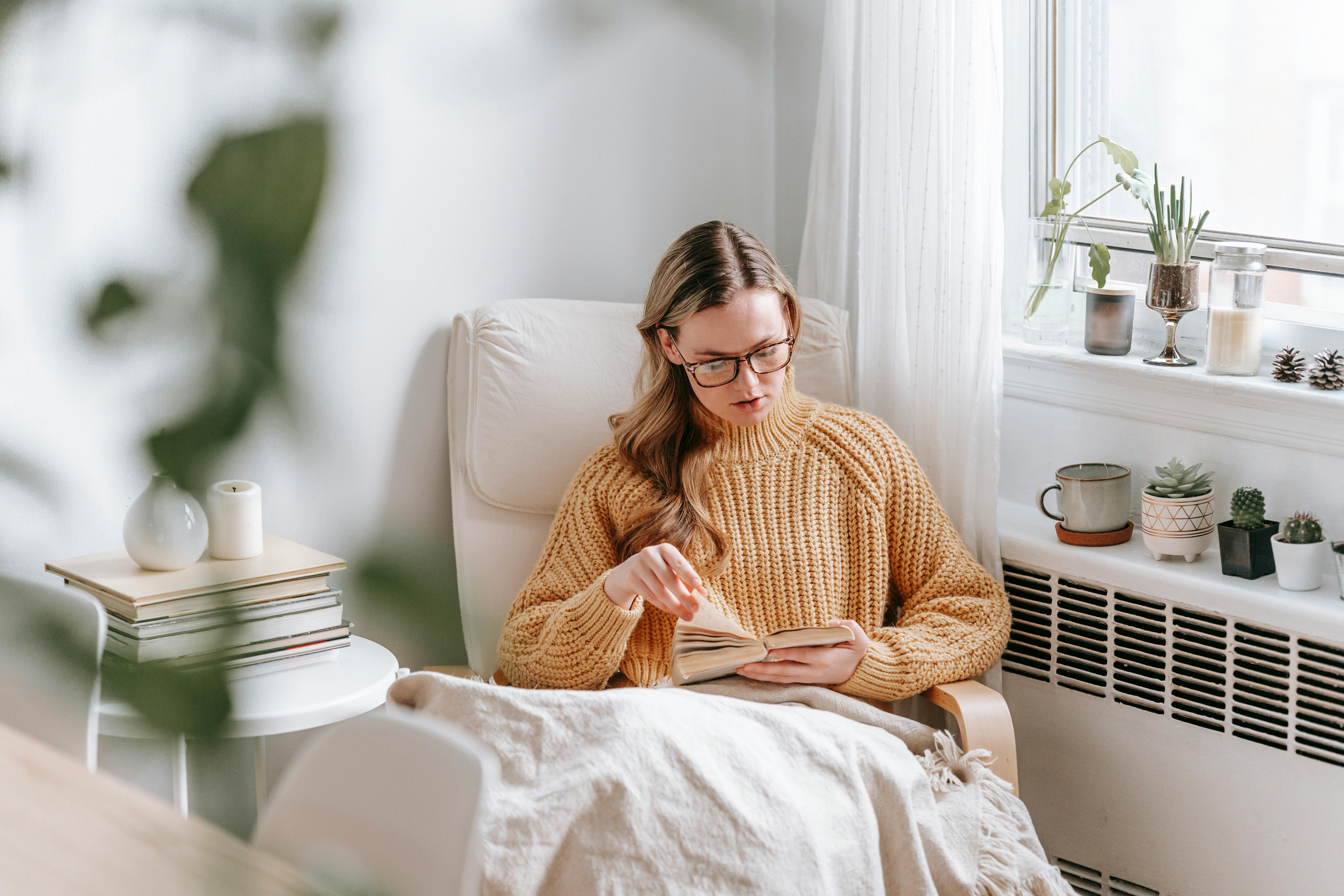 young woman reading book in cozy armchair