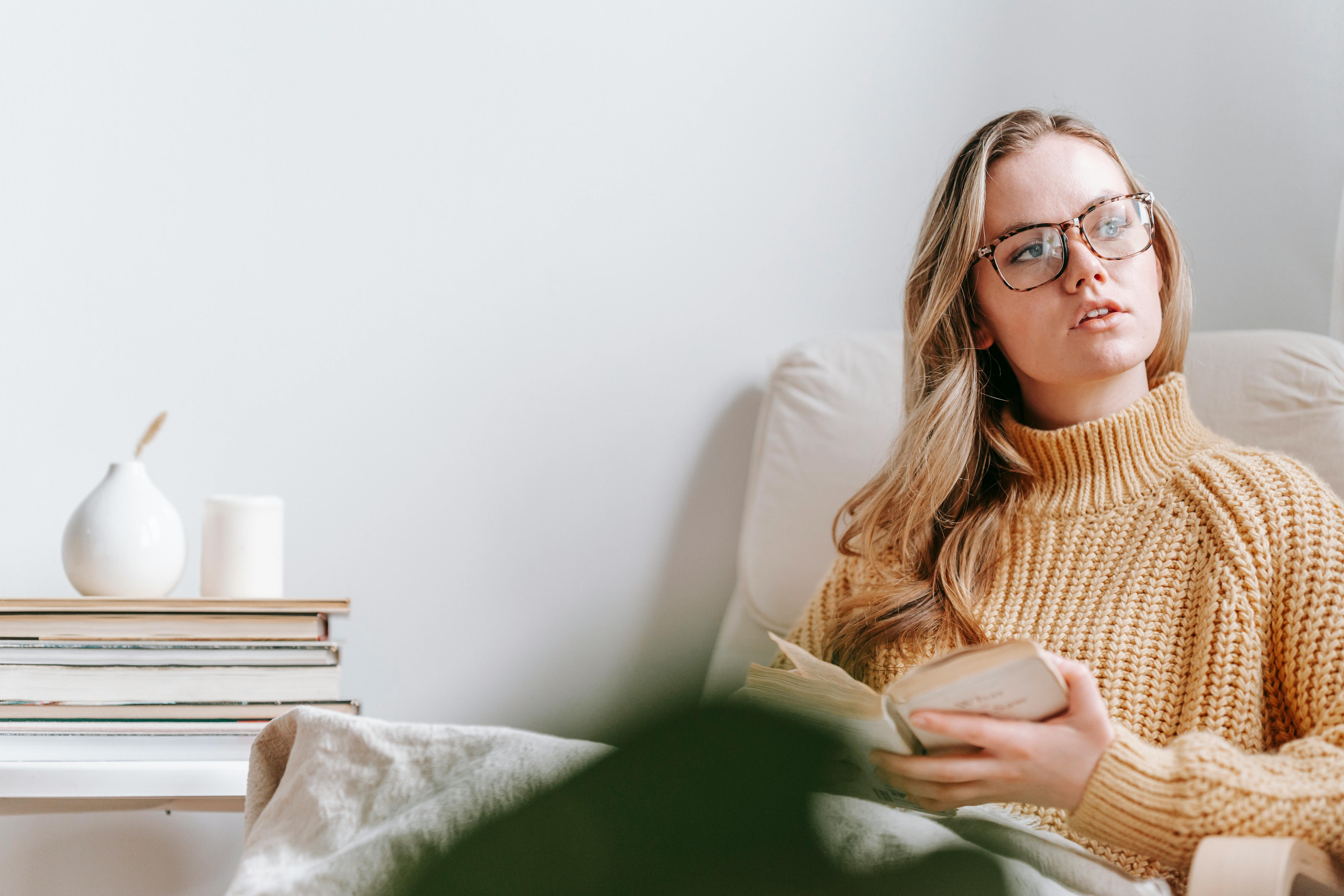 young pensive woman with book in armchair