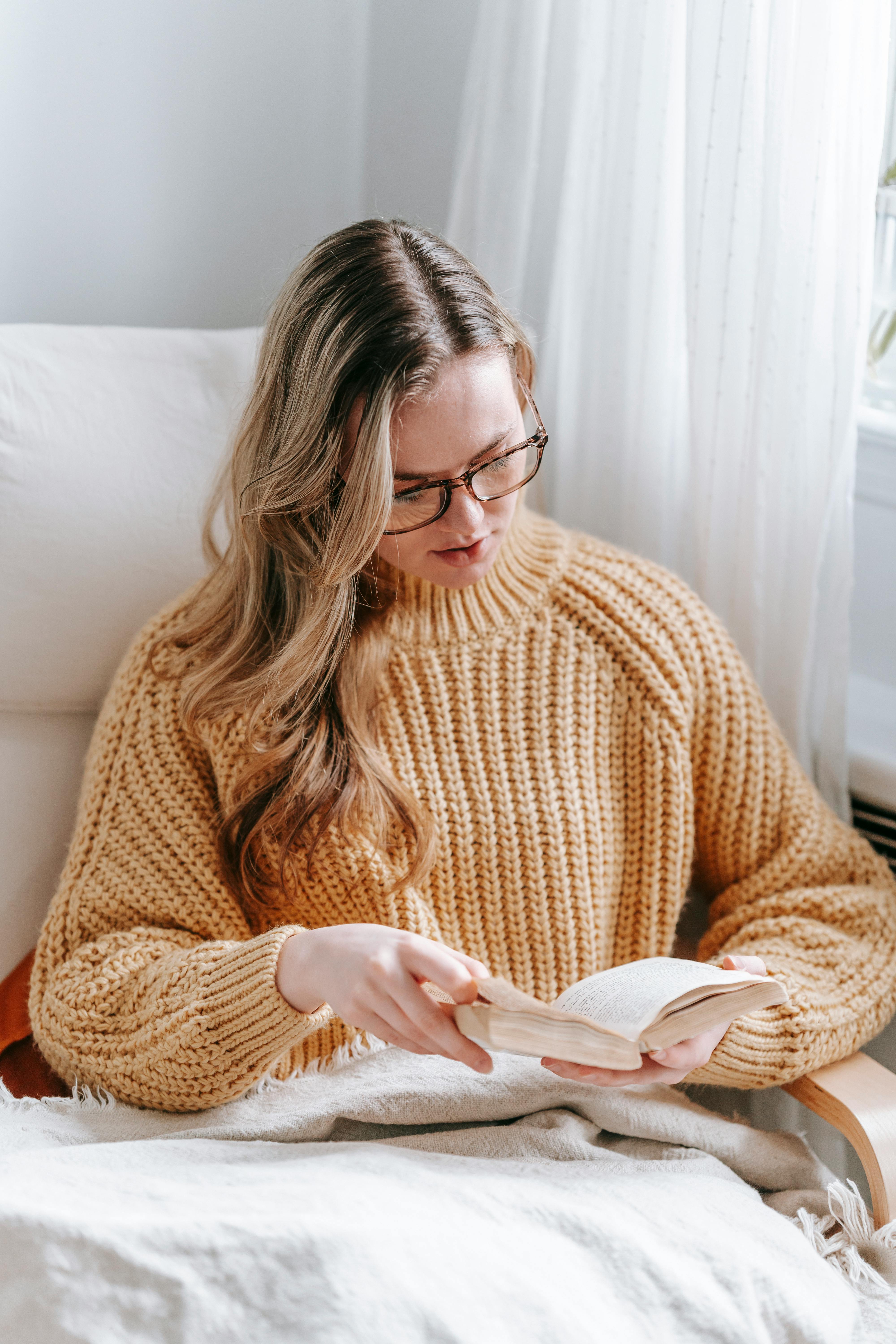 young woman reading book in room