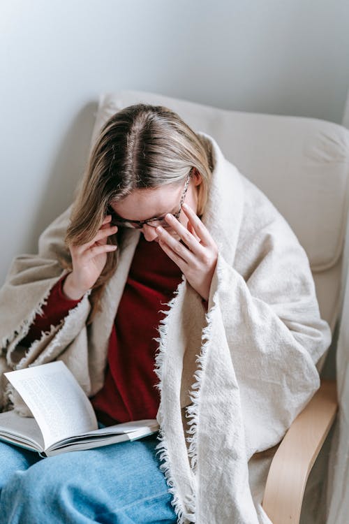 Woman sitting in armchair with book in cozy room