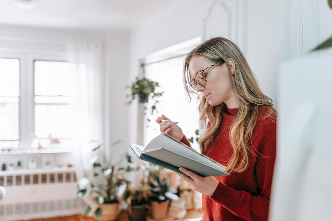 Smart lady reading textbook during breakfast at home