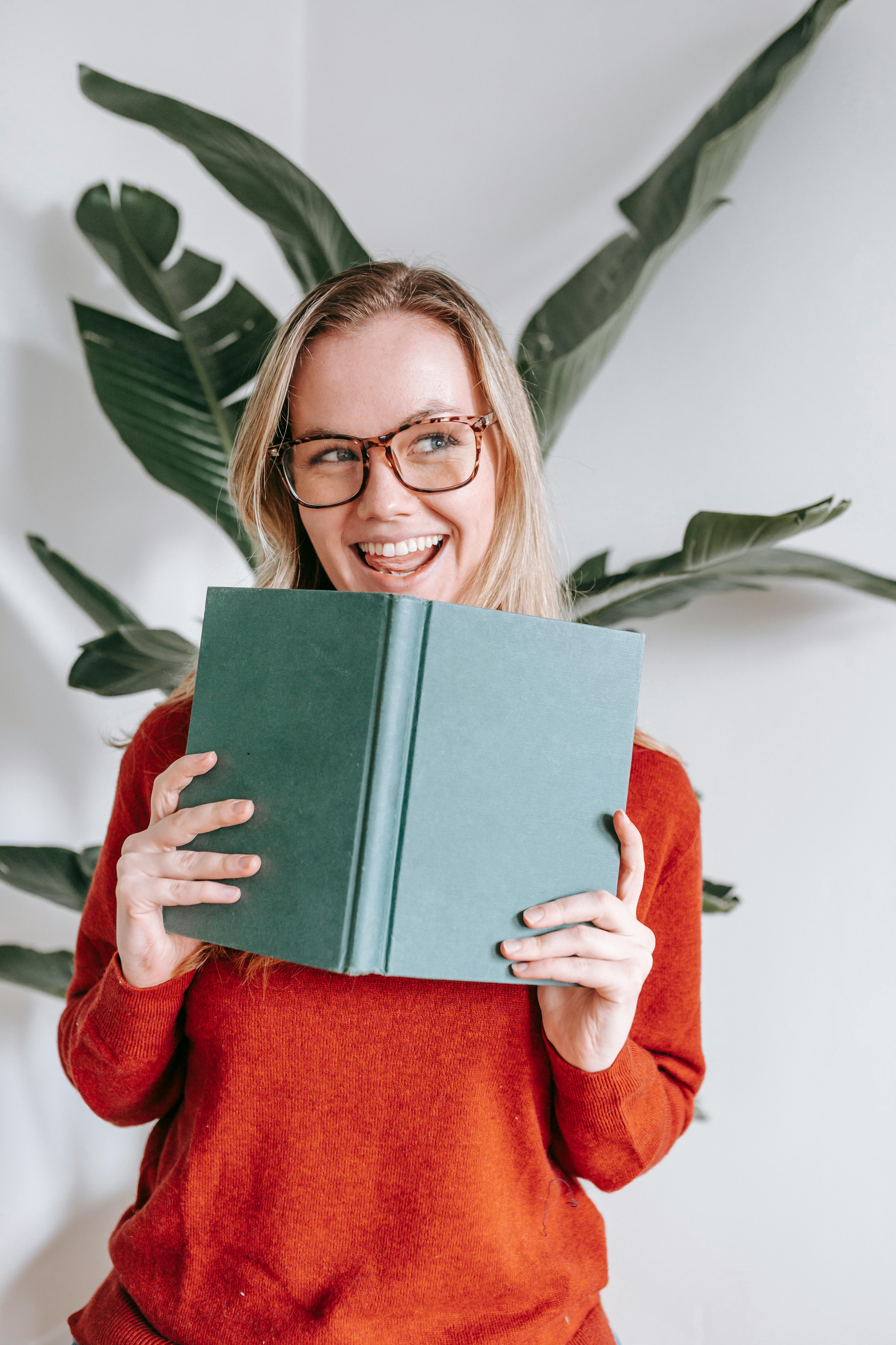 amazed young lady smiling and looking away with book in hands