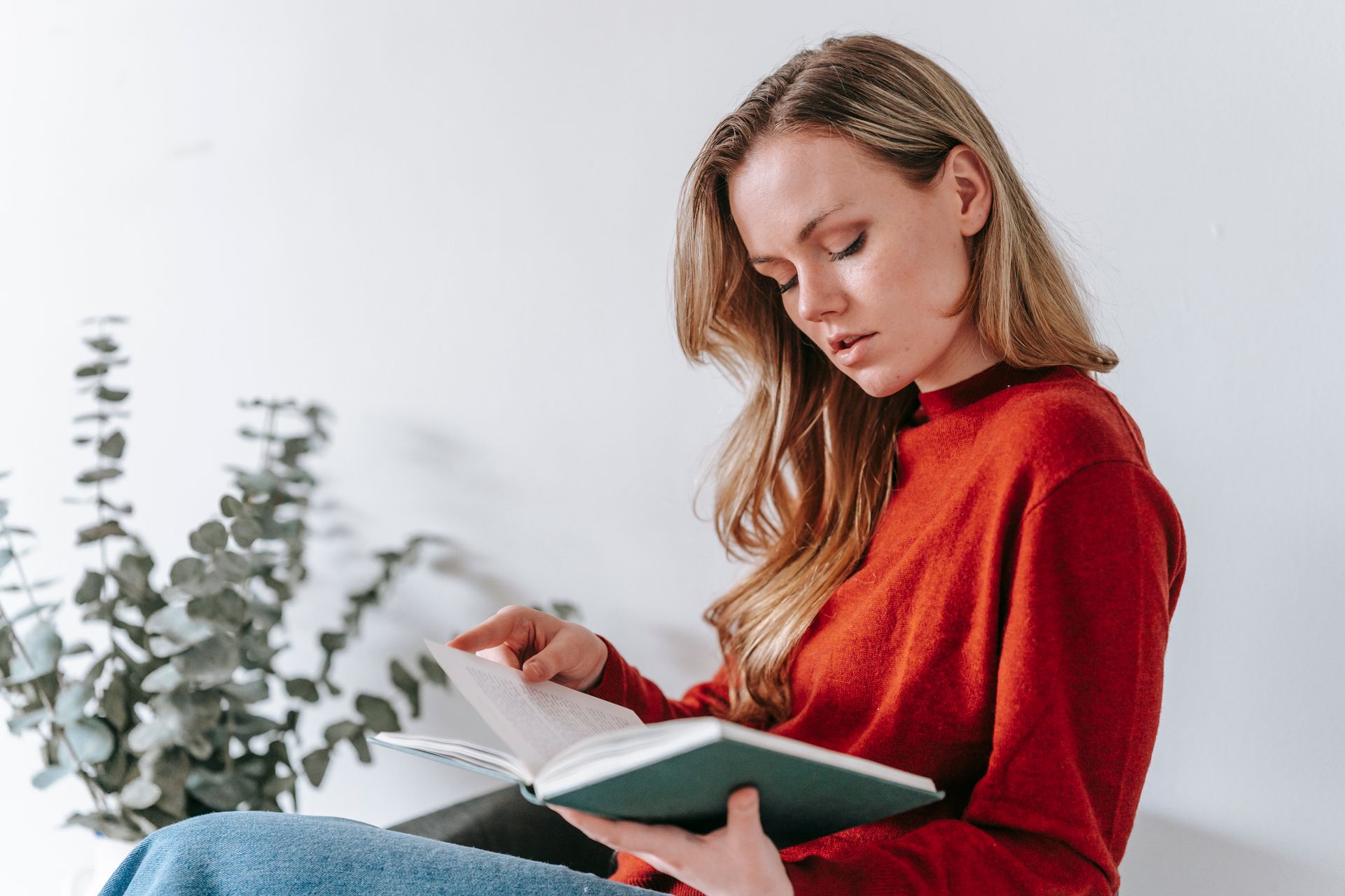 Calm young lady reading interesting fiction during weekend at home