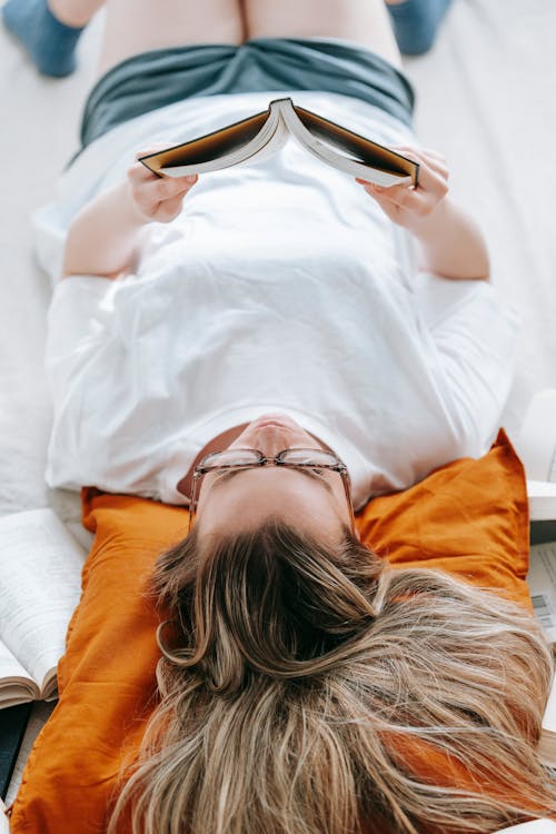 Free Relaxed young woman spending free time at home with book Stock Photo