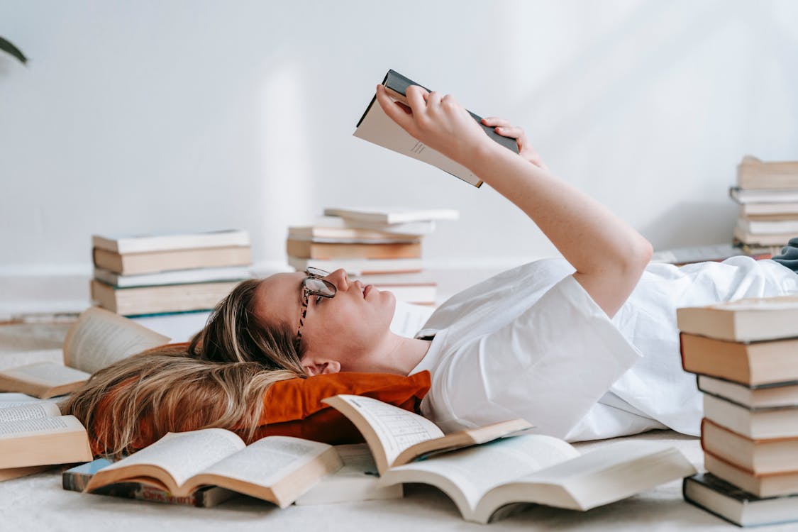 Free Young smart woman reading book on floor Stock Photo