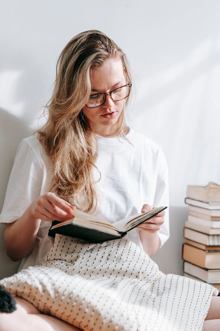 Thoughtful Woman Reading Book At Wall