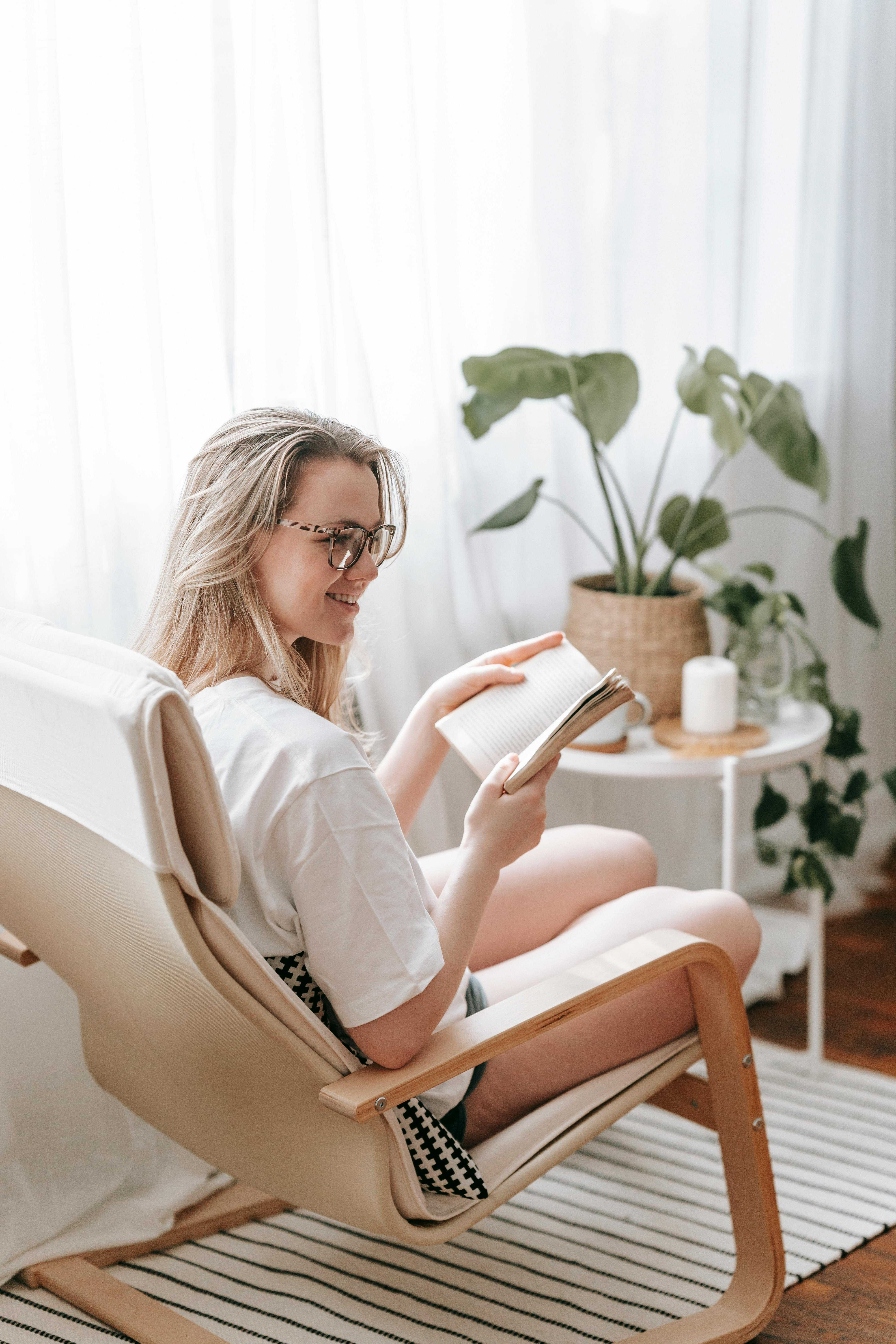 cheerful woman reading book in armchair