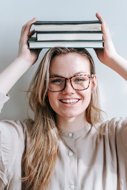 Cheerful woman with books on head