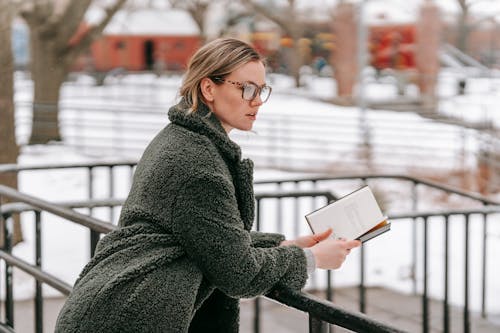 Young woman with book leaning on railing