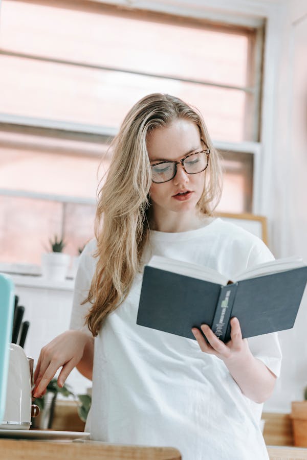 Focused woman reading book in kitchen