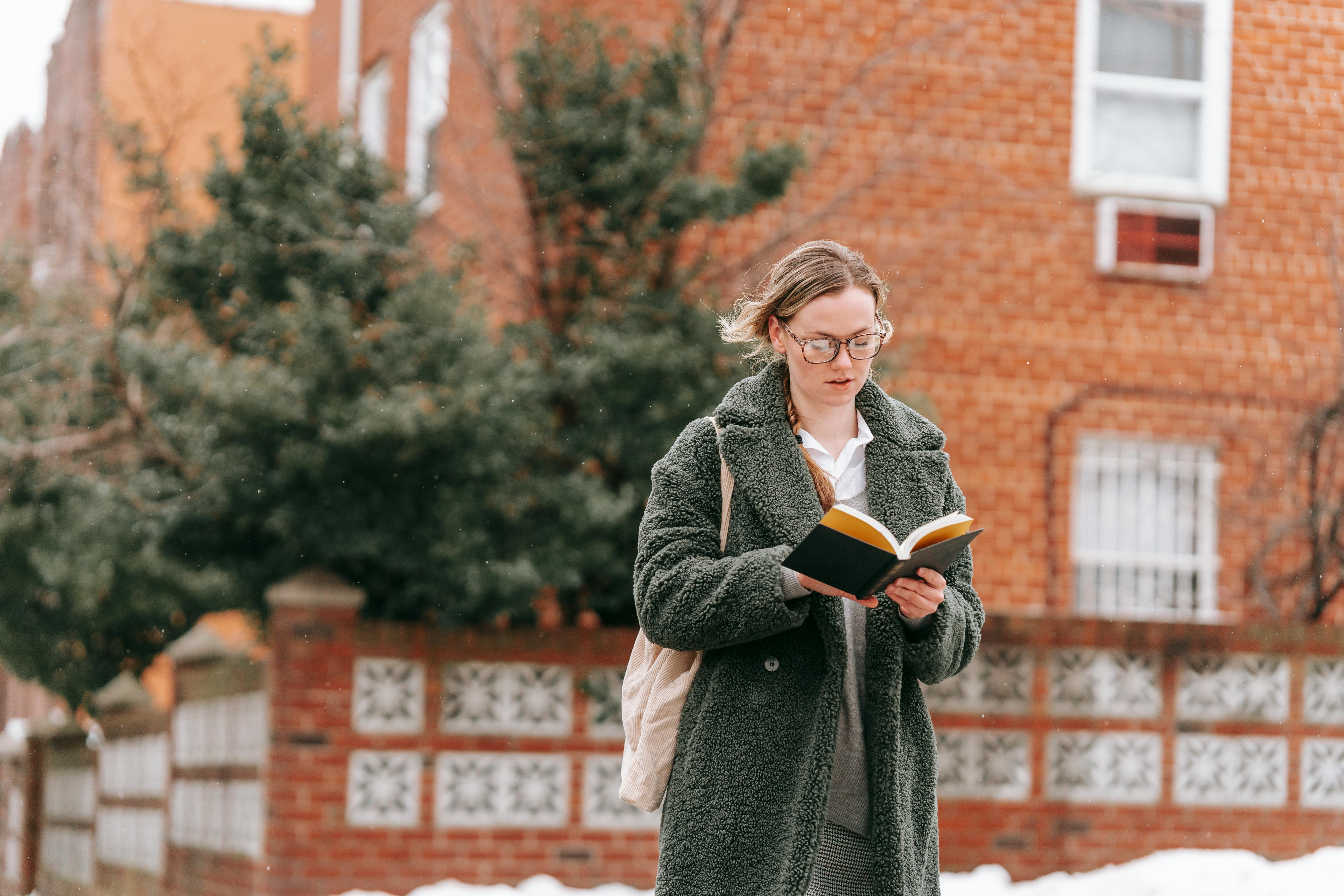 Serious woman reading book on street