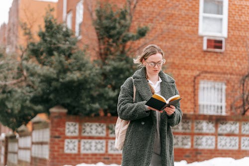 Serious woman reading book on street