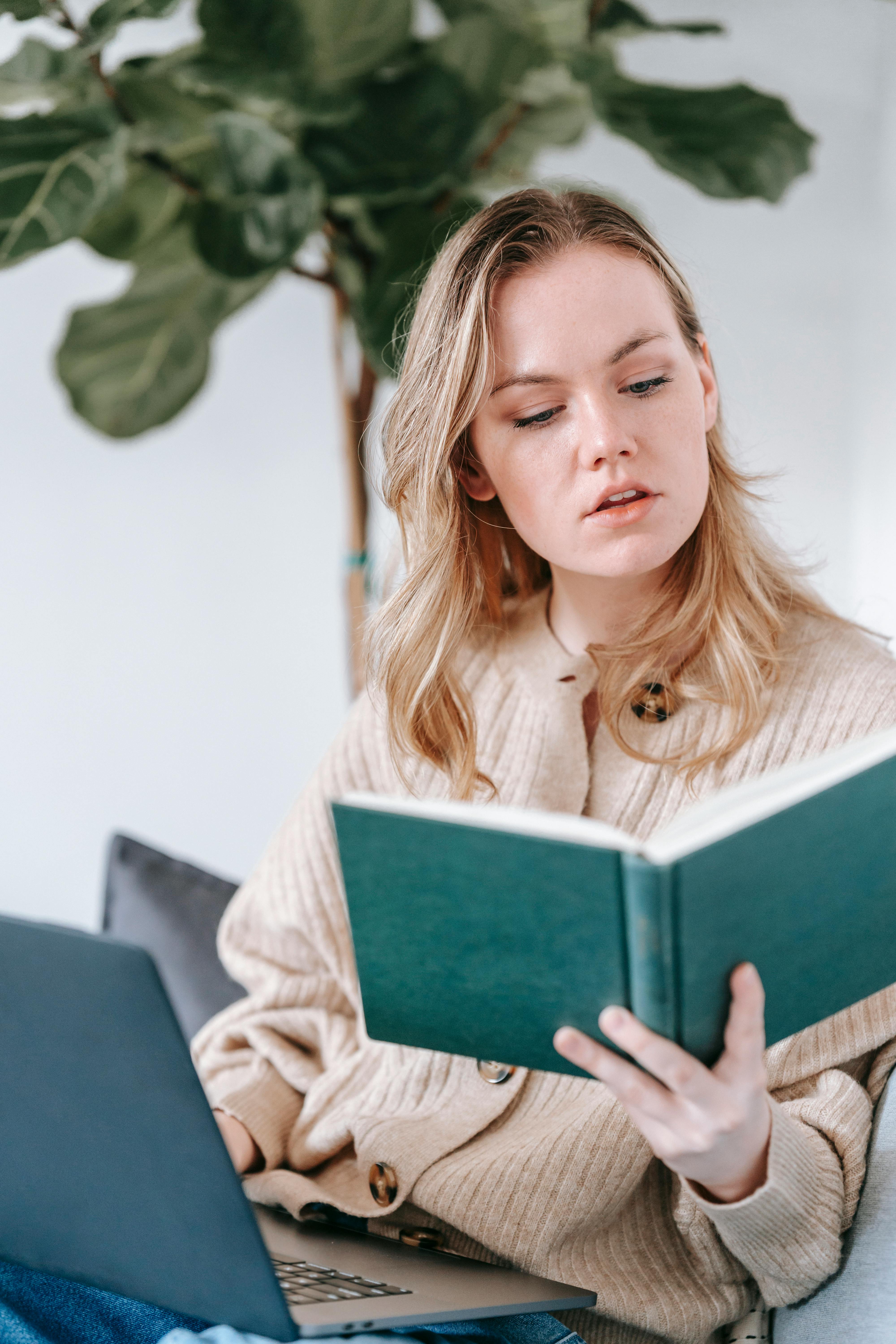 attentive woman with laptop reading book