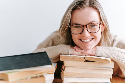 Free Smiling Woman Leaning on Stack of Books Stock Photo