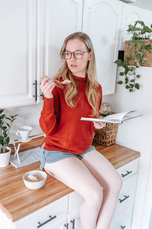 Woman Eating Ice Cream while Holding a Book