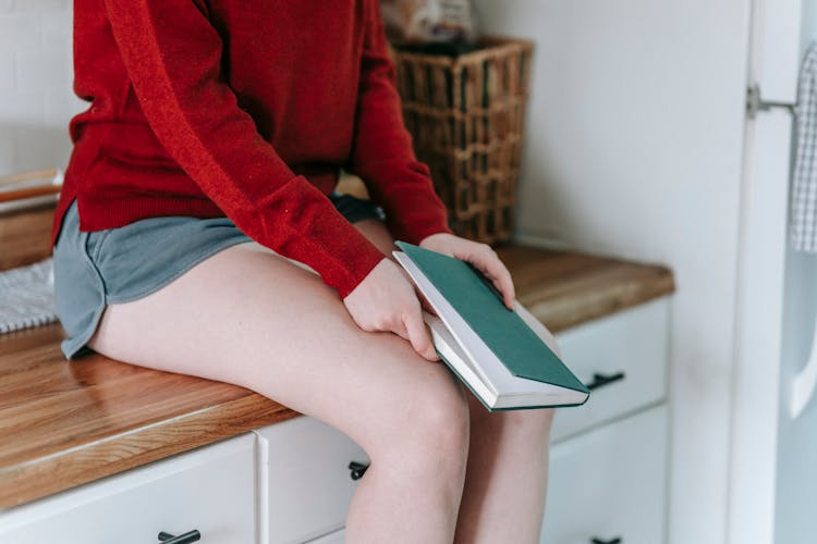 A Woman Sitting On Kitchen Countertop