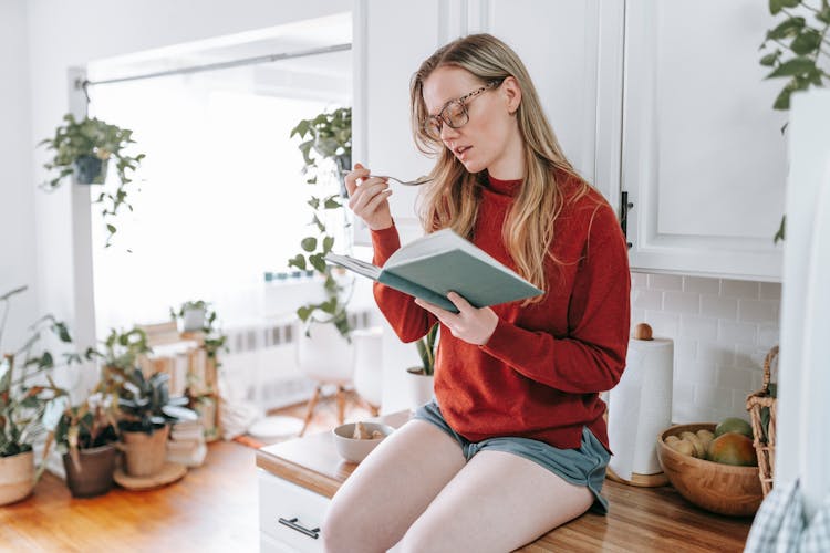 A Woman Eating Ice Cream While Reading