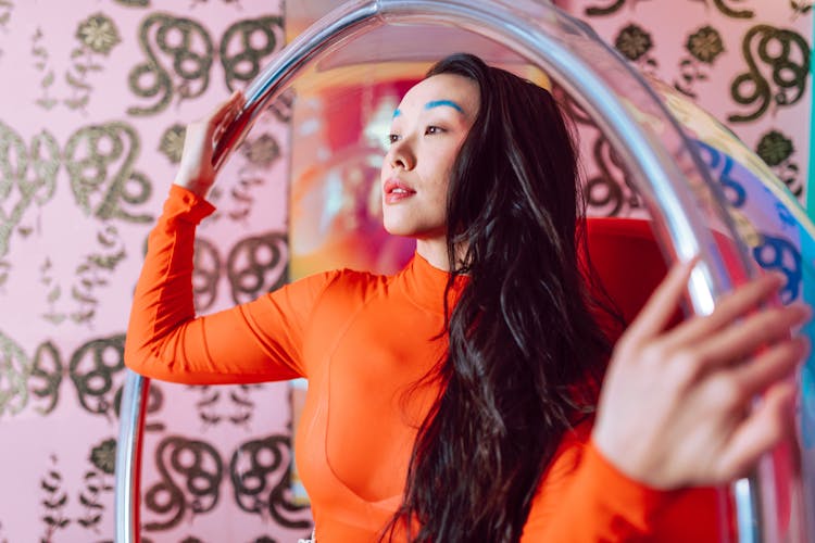 A Woman Wearing Orange Long Sleeve Top With Blue Eyebrows