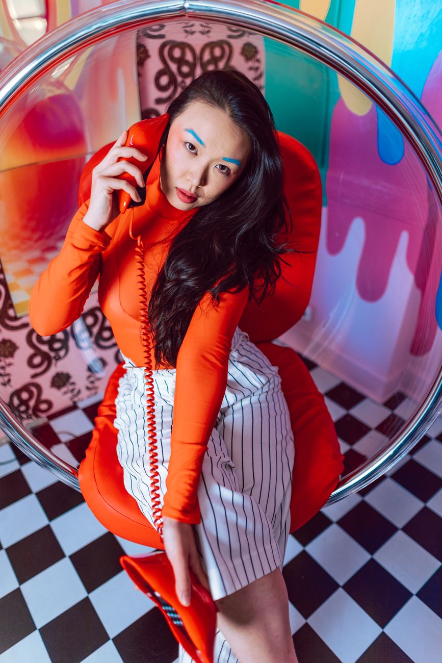 Stylish woman in vibrant setting with retro phone, exuding modern fashion flair.