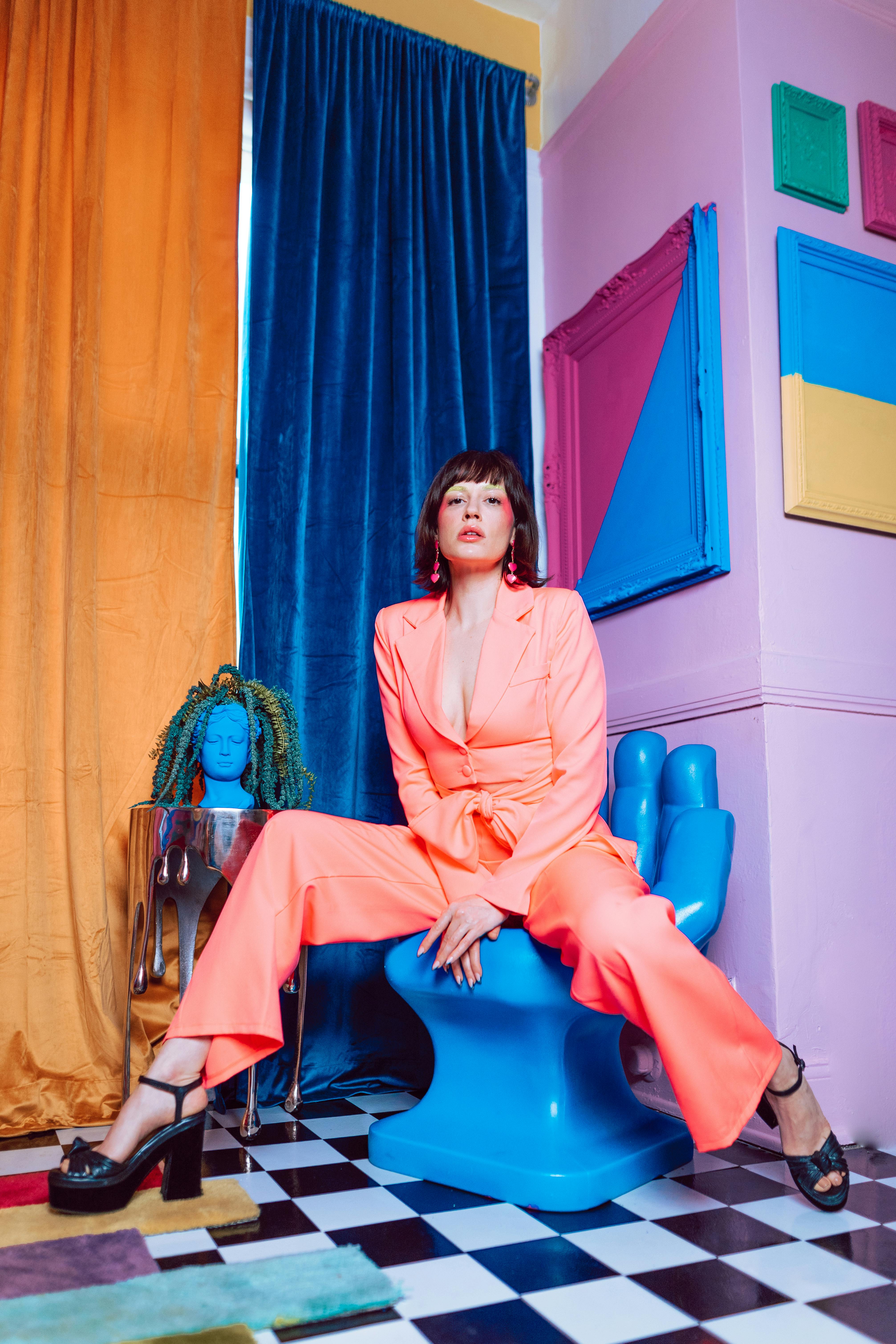 woman in pink long sleeve dress sitting on blue leather chair