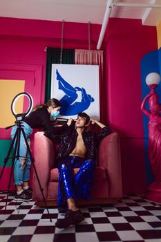 Vibrant fashion photoshoot with makeup artist in a colorful studio setting.