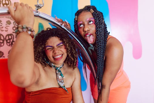 Two friends express joy and vibrant style with colorful makeup and playful poses against a lively backdrop.