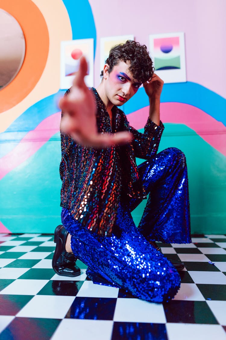 A Man Sparkly Top And Pants Kneeling On A Floor