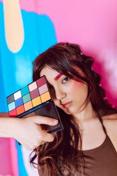 Artistic portrait showcasing bold makeup and colorful style on a vibrant background.