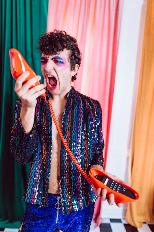 A Person with Vibrant Eye Makeup Screaming at a Telephone