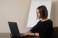 Female operator working on laptop with headphones with microphone