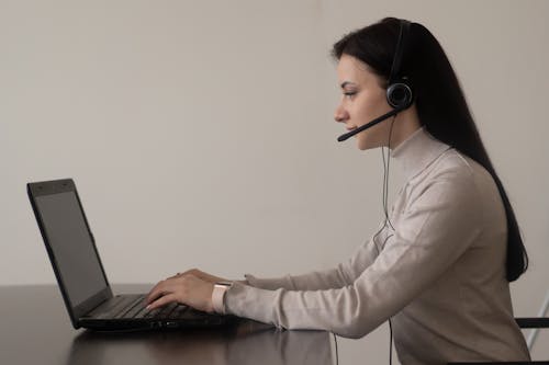 Lady with headphones with microphone working on netbook