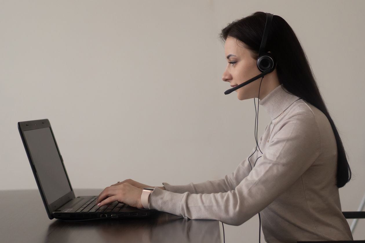Operadora de soporte con auriculares trabajando en un portátil