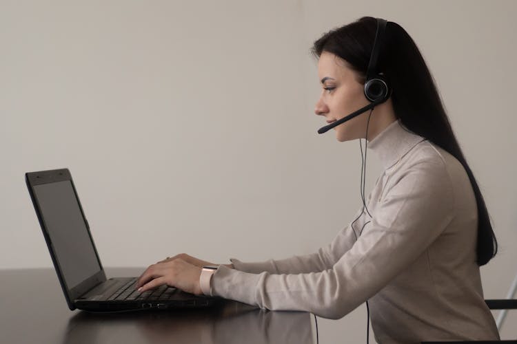 Lady With Headphones With Microphone Working On Netbook