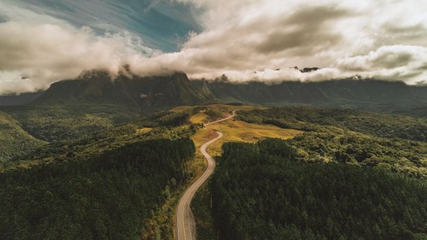 A breathtaking aerial view showing the winding road through the lush, mountainous landscape of Urubici, SC, Brazil.