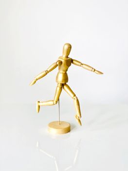 A wooden artist's mannequin striking a dynamic pose against a white background.