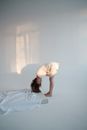 Young woman bending forward near mattress